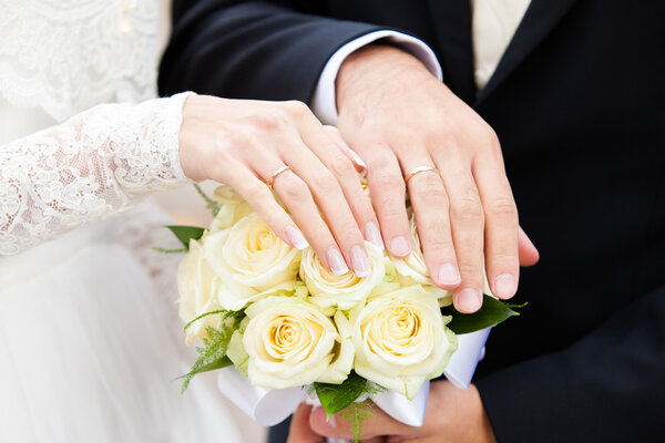 hands of  groom and the bride on a yellow bouquet