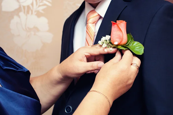 Boutonnière du marié et la main des mères — Photo