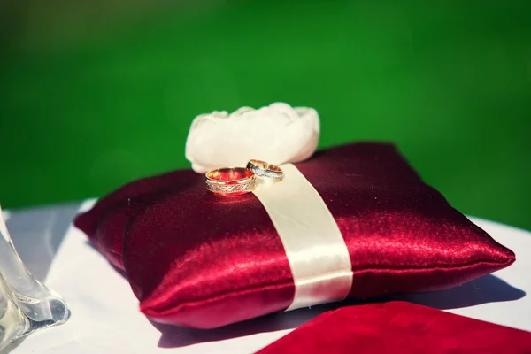 Anéis de casamento no travesseiro vermelho — Fotografia de Stock