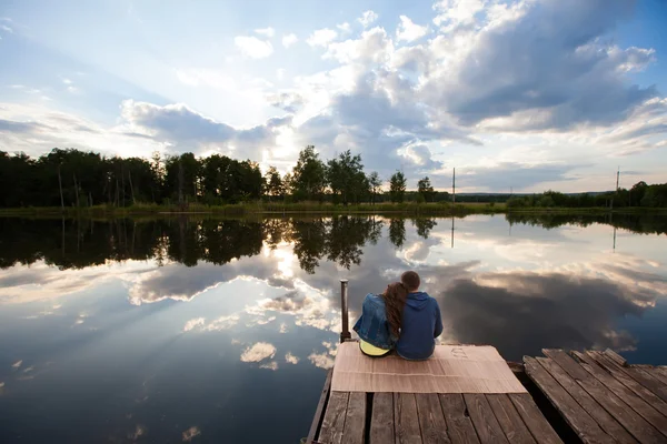 Amoureux assis sur la rive au coucher du soleil — Photo