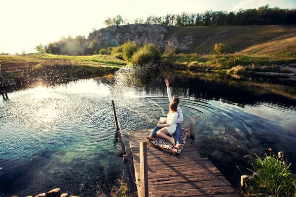 Amoureux assis sur la rive au coucher du soleil — Photo