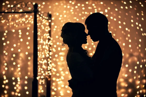 Silhouettes of lovers on a background garlands — Stock Photo, Image