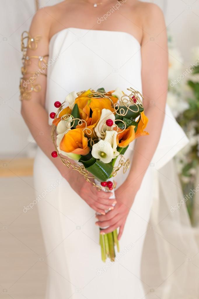 the bride holds an orange bouquet in hand