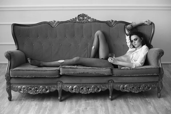 Beautiful girl in stockings lies on an ancient sofa — Stock Photo, Image