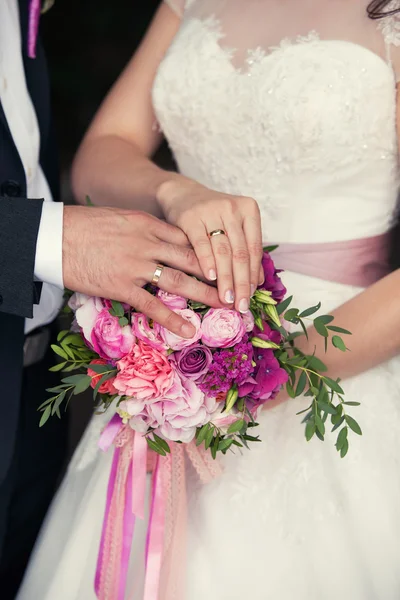 Mains du marié et de la mariée sur un bouquet de mariage — Photo