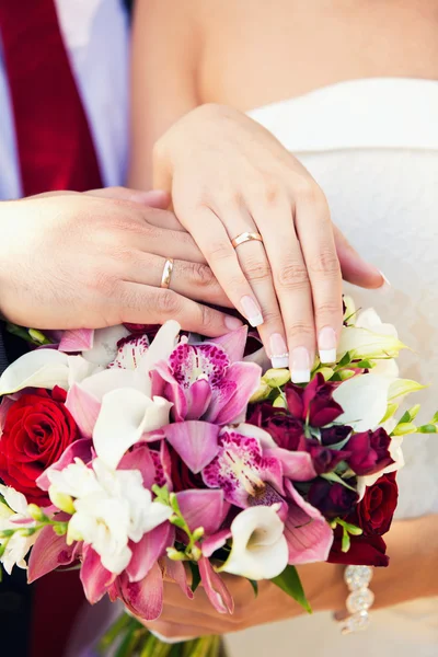 Las manos del novio y la novia en un ramo de bodas — Foto de Stock