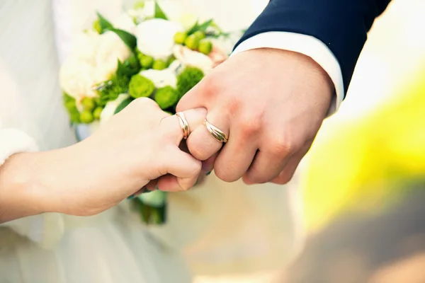 Mains du marié et de la mariée sur un bouquet de mariage — Photo