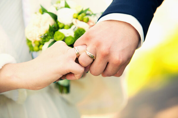 hands of groom and bride on a wedding bouquet