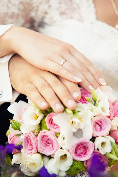 Mains du marié et de la mariée sur un bouquet de mariage — Photo