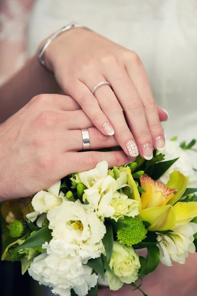 Mains du marié et de la mariée sur un bouquet de mariage — Photo