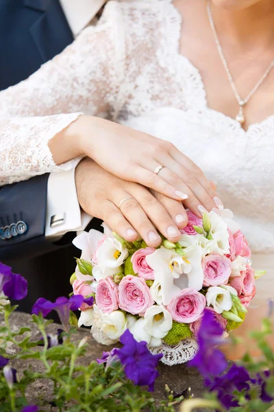 Las manos del novio y la novia en un ramo de bodas — Foto de Stock