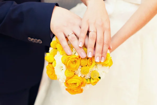 Mains du marié et de la mariée sur un bouquet de mariage — Photo