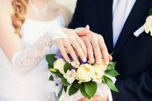 Mains du marié et de la mariée sur un bouquet de mariage — Photo