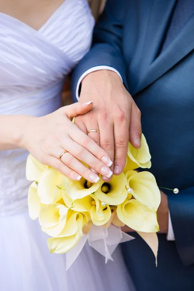 Las manos del novio y la novia en un ramo de bodas — Foto de Stock