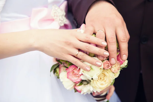 Mains du marié et de la mariée sur un bouquet de mariage — Photo