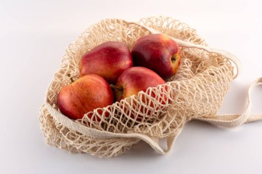 Beyaz arkaplandaki bir eko torbasında kırmızı elmalar