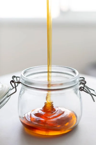 fresh natural buckwheat honey is poured into a jar
