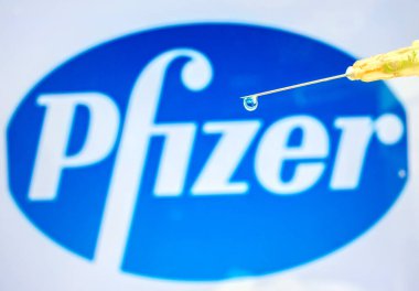 Viyana Avusturya 28 Ocak 2021, Pfizer logosuna karşı sıvı atımlı şırınga. Çok uluslu ilaç şirketi Coronavirus aşı konsepti.
