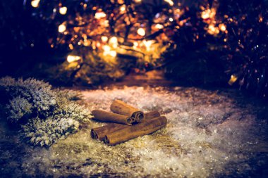 Arka plan bulanık ışık ve çam dalları üzerinde kar kar ile tarçın sopa.