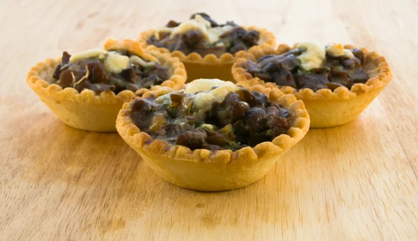 Mantar ve ahşap bir masa üzerine peynir pişmiş tartlets