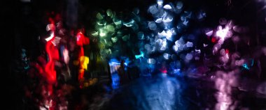 Gece bulanık şehir ışıkları yağmurlu bir ön camdan yansıyor.