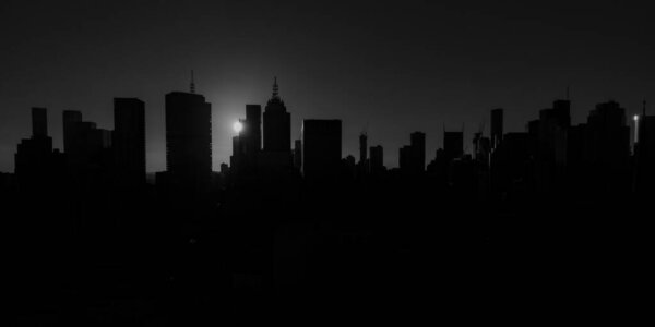 Melbourne city skyline silhouetted by a dramatic sunset in black and white