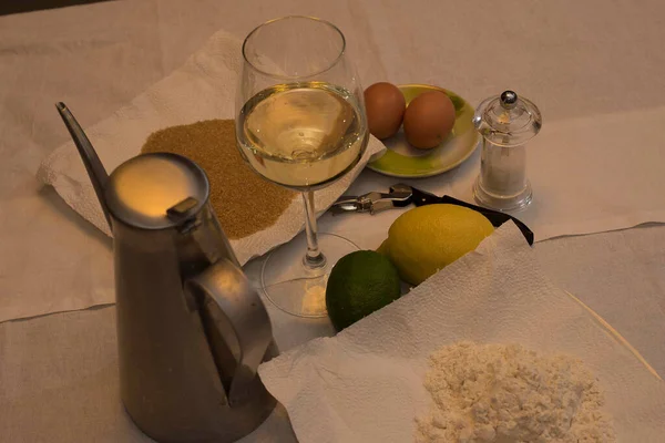 Chiffon cake ingredients, glass of Moscato d'Asti, lemons, raisins, brown sugar, flour 00, on background of white fabric, full frame Nikon d750