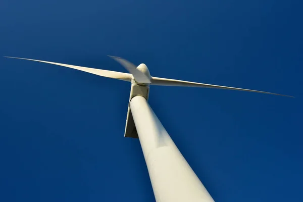 Close-up of a tower wind generator, which stands out against the backdrop of a blue sky. Turbine that saves the environment and produces green energy.