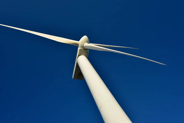 Close-up of a tower wind generator, which stands out against the backdrop of a blue sky. Turbine that saves the environment and produces green energy.