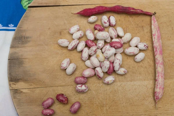 Borlotti fasulyeleri ahşap kesme tahtasına soyulmuş. Beyaz, kırmızı fasulye, benekli, çıplak. Ahşap kapsüller ve çapraz masa örtüsü. İtalyan kısa makarna malzemeleri. Fasulyeli makarna.
