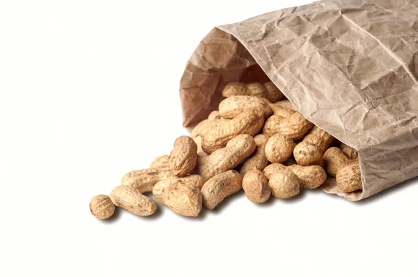 Amendoins e saco de papel no fundo branco — Fotografia de Stock