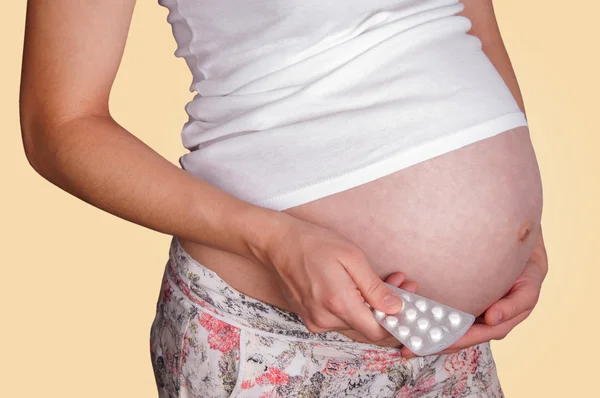 Kobieta w ciąży gospodarstwa pigułki. — Zdjęcie stockowe