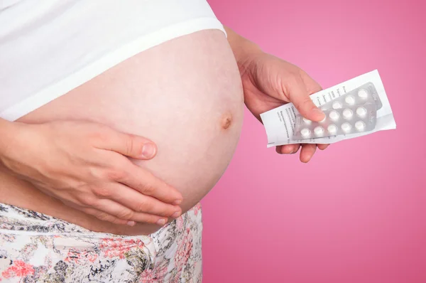 Pregnant woman holding pills. Stock Snímky