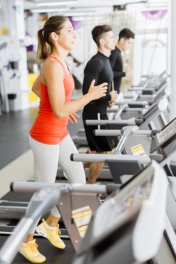 Bir grup insan bir spor salonunda koşu bandı kullanarak