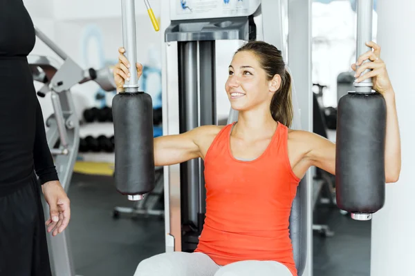 Entraîneur donnant des instructions à une femme dans une salle de gym — Photo