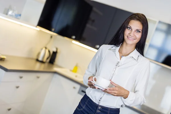 Mujer sosteniendo una taza en una cocina — Foto de Stock