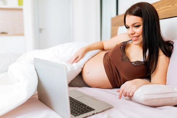 Schwangere benutzt Laptop im Bett — Stockfoto