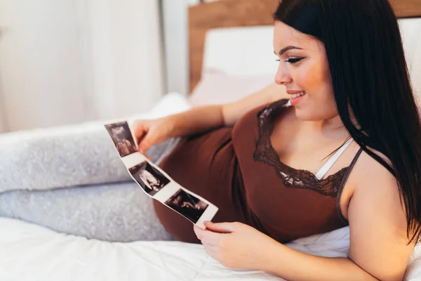 Schwangere schaut sich Scan von Baby an — Stockfoto