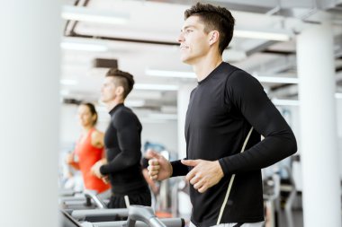 Bir grup insan bir spor salonunda koşu bandı kullanarak