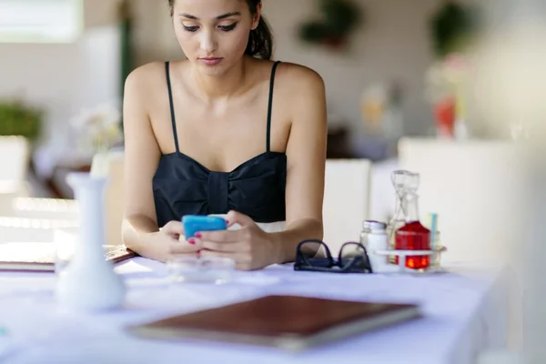 Vacker kvinna med telefonen i restaurang — Stockfoto