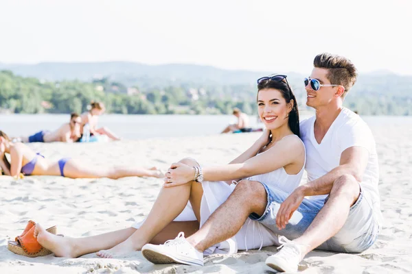 Romântico jovem casal sentado em uma praia — Fotografia de Stock