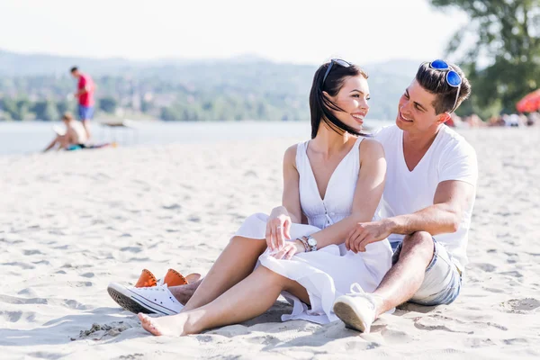 Romantisches junges Paar sitzt an einem Strand — Stockfoto