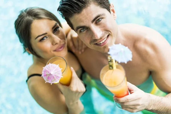 Pareja sonriendo y bebiendo un cóctel en una piscina — Foto de Stock