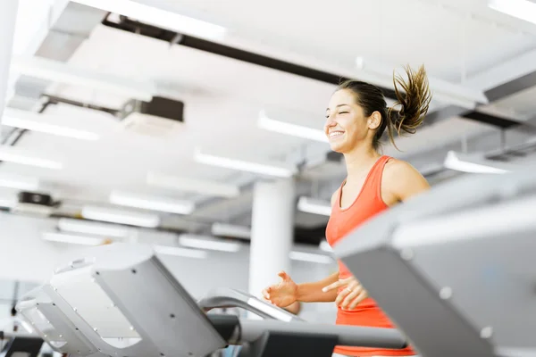 Kvinna som körs på ett löpband i gym — Stockfoto