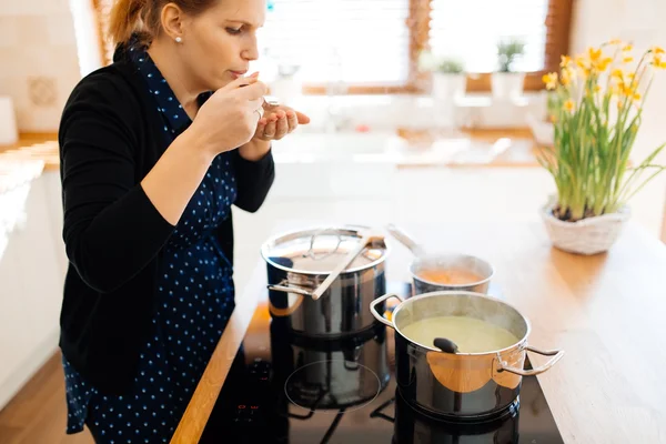 Hospodyňka, chutnající jídlo v kuchyni — Stock fotografie