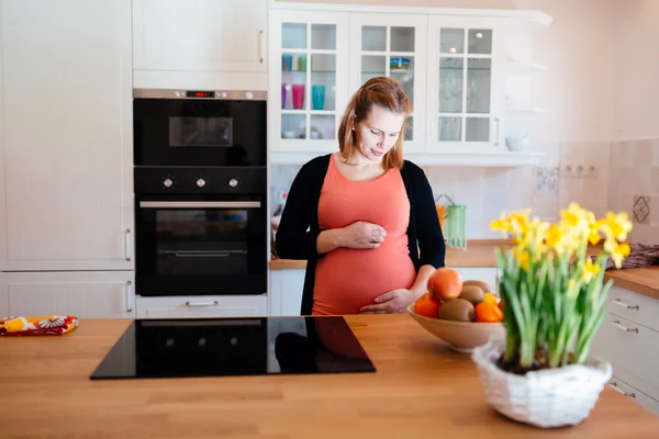 Mulher grávida bonita na cozinha — Fotografia de Stock