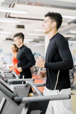 Bir grup insan bir spor salonunda koşu bandı kullanarak