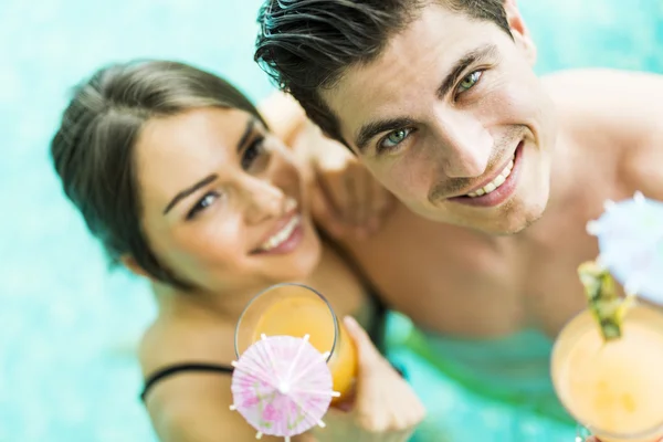 Coppia sorridente e bere un cocktail in piscina — Foto Stock