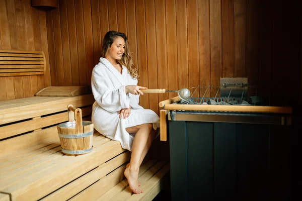 Hermosa mujer sentada en sauna finlandesa — Foto de Stock