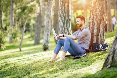 Parkta tablet kullanan bir işadamı